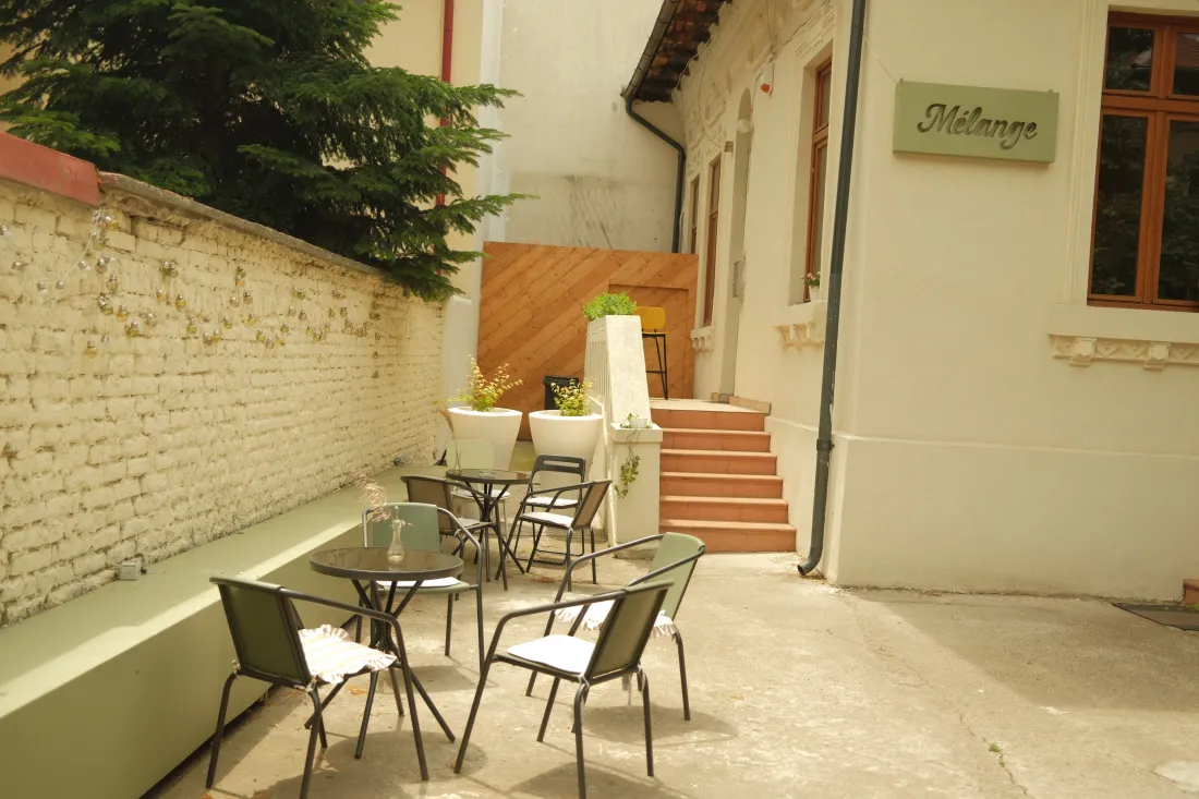Terasa din grădină, cu mese de cafenea sub firma Mélange